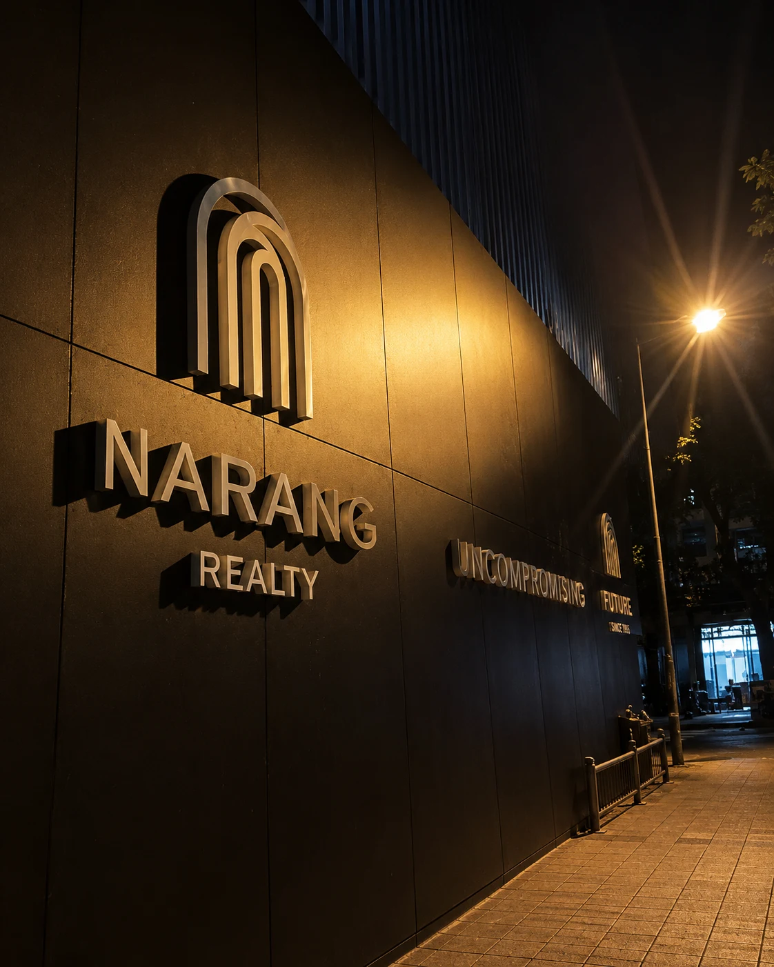 Illuminated Narang Realty architectural signage at night
